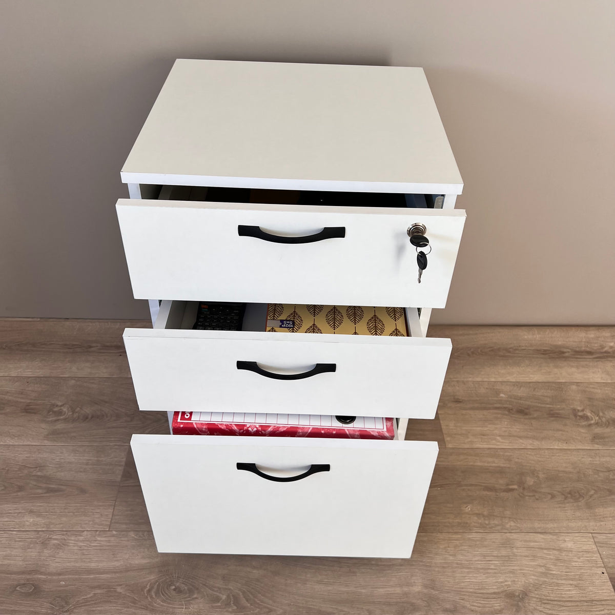 Caisson bureau blanc – tiroir inférieur ouvert avec classeurs rouges et archives